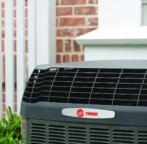 A Trane air conditioner installed beside a brick home